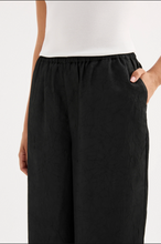 Load image into Gallery viewer, Black wide-leg pants worn by a person on a white background