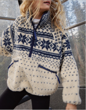 Load image into Gallery viewer, Person wearing a white fleece jacket with blue patterns sitting on a bench.